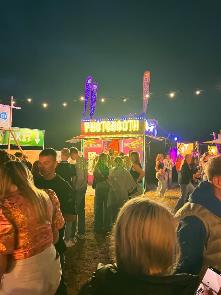 PHOTOBOOTH XXL met verlicht front en beachvlaggen op een festival 's nachts