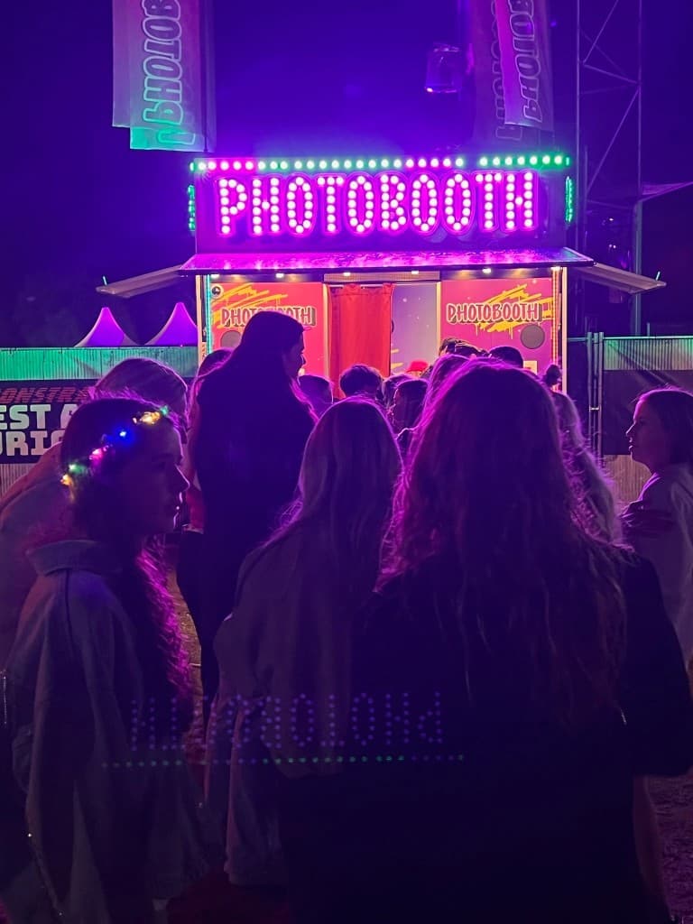 Publiek rond de verlichte PHOTOBOOTH XXL op een festival 's nachts