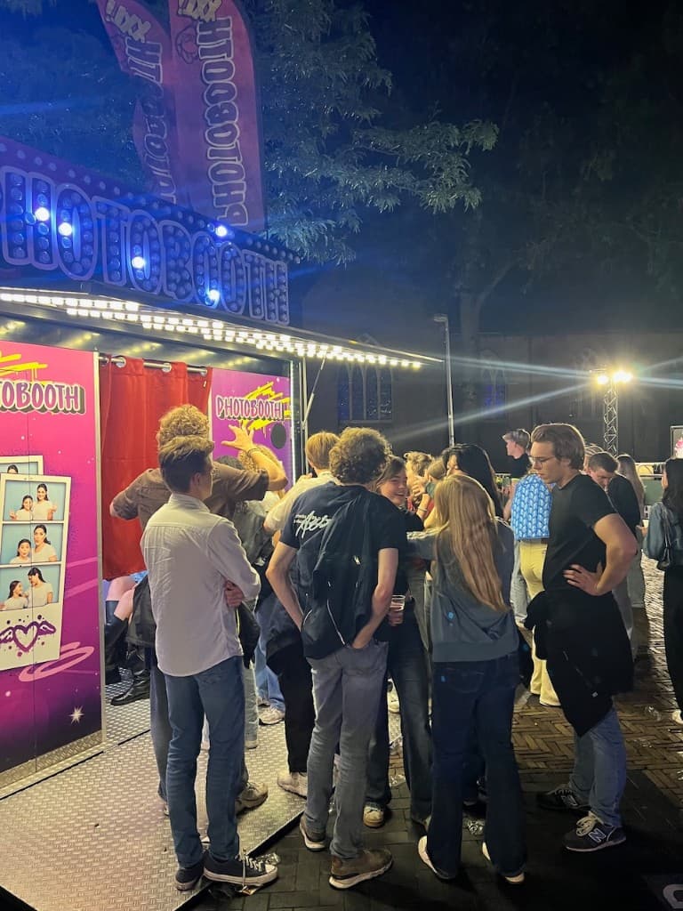 PHOTOBOOTH XXL met rode gordijnen op een druk plein in de avond