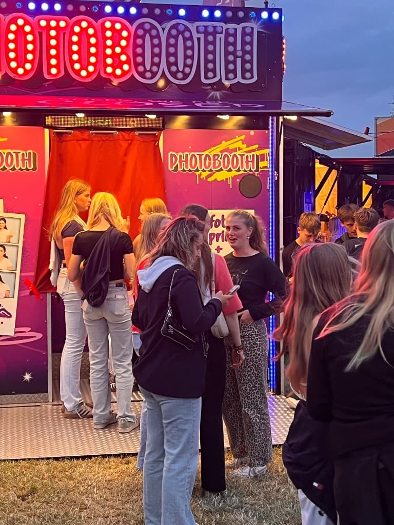 Publiek wacht bij de verlichte PHOTOBOOTH XXL op een grasveld